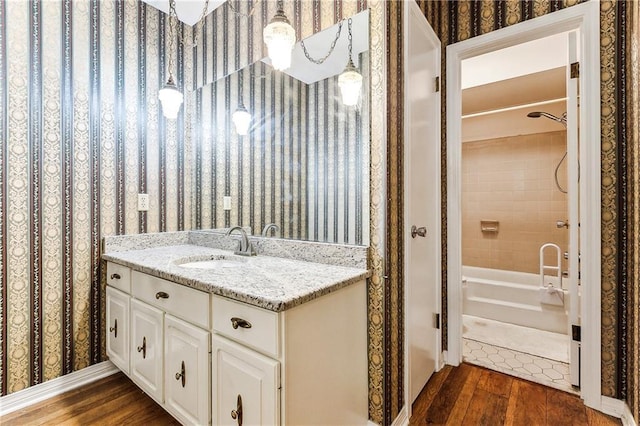 bathroom with wood-type flooring, tiled shower / bath combo, and vanity