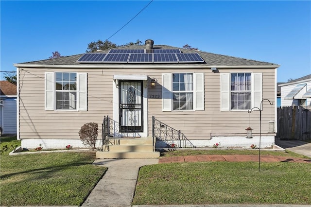 bungalow-style house with a front yard and solar panels