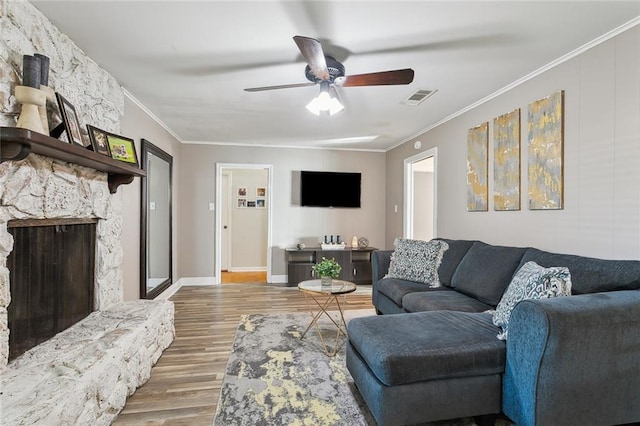 living room with hardwood / wood-style flooring, ceiling fan, ornamental molding, and a fireplace