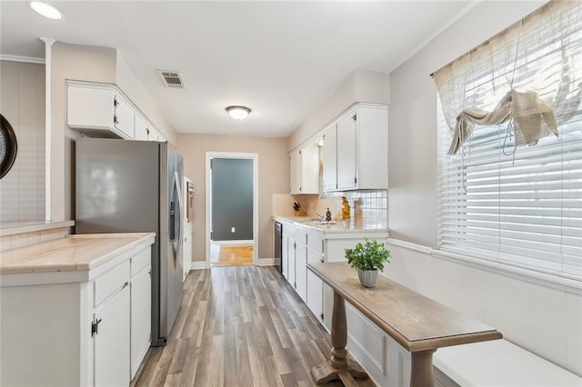 kitchen with sink, stainless steel appliances, tasteful backsplash, light hardwood / wood-style floors, and white cabinets