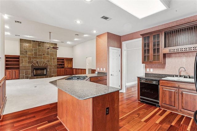 kitchen featuring a fireplace, dishwasher, a center island, sink, and light stone countertops