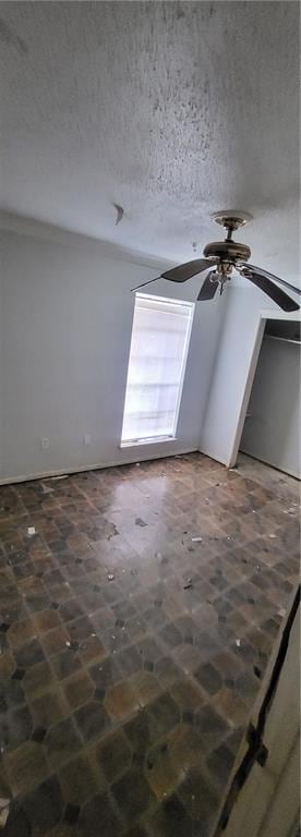 empty room with ceiling fan and a textured ceiling