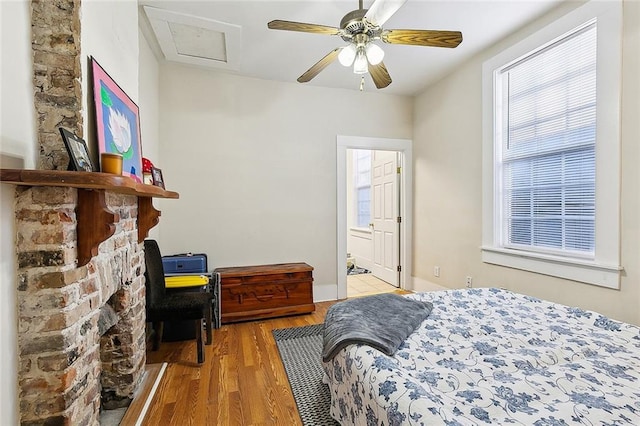 bedroom with light wood-type flooring, ceiling fan, multiple windows, and ensuite bath