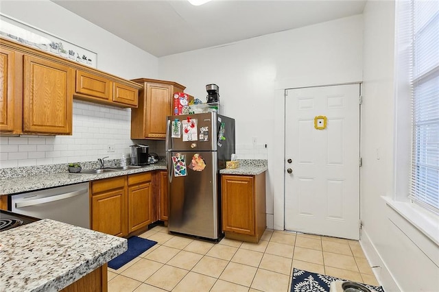 kitchen with decorative backsplash, sink, appliances with stainless steel finishes, light tile patterned floors, and light stone counters