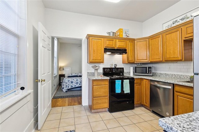 kitchen featuring light stone countertops, backsplash, appliances with stainless steel finishes, and light tile patterned flooring