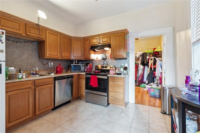 kitchen featuring decorative backsplash, sink, stainless steel appliances, and light tile patterned flooring