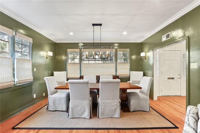 dining room with an inviting chandelier, crown molding, and light hardwood / wood-style flooring