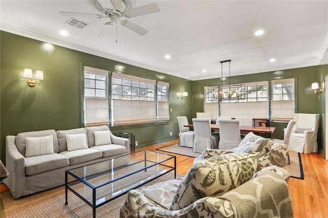 living room featuring ceiling fan, crown molding, and light wood-type flooring