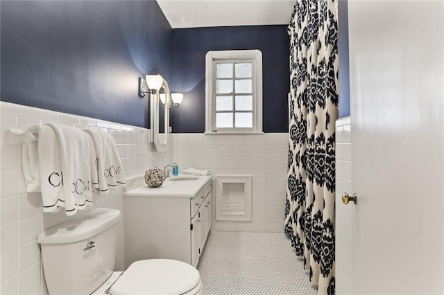 bathroom with tile patterned floors, toilet, vanity, and tile walls