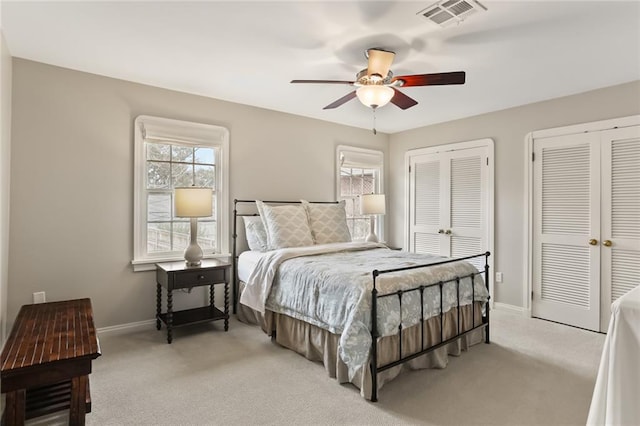 carpeted bedroom featuring ceiling fan, multiple closets, and multiple windows