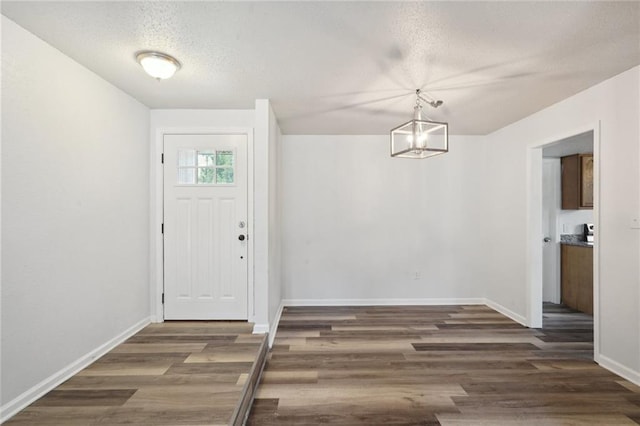 foyer with a textured ceiling, dark hardwood / wood-style floors, and a notable chandelier