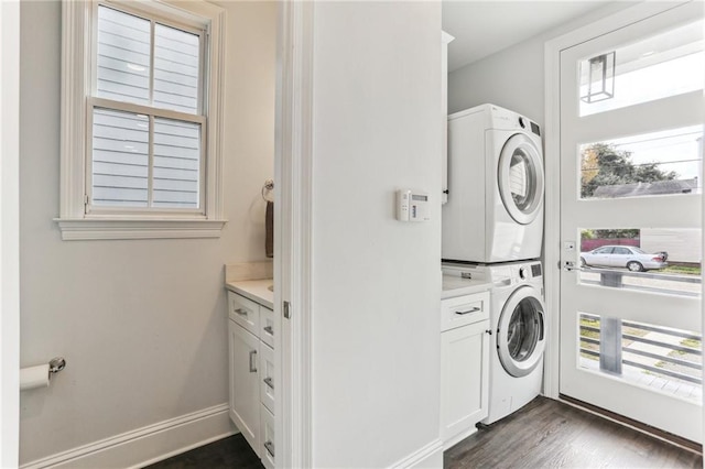 washroom featuring stacked washer and dryer, dark hardwood / wood-style floors, and cabinets