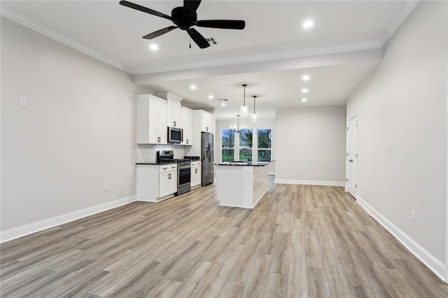 kitchen with white cabinetry, appliances with stainless steel finishes, hanging light fixtures, a kitchen island, and ceiling fan with notable chandelier