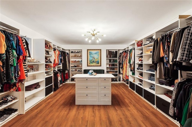 spacious closet featuring wood-type flooring and a notable chandelier