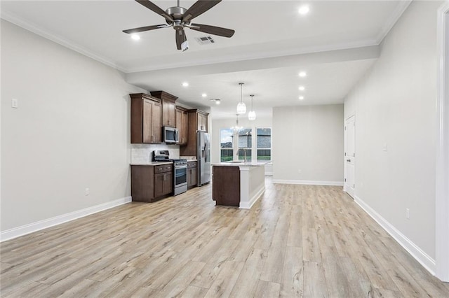 kitchen with light hardwood / wood-style floors, an island with sink, appliances with stainless steel finishes, hanging light fixtures, and ceiling fan with notable chandelier