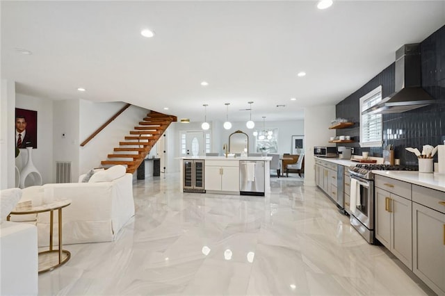 kitchen featuring appliances with stainless steel finishes, gray cabinetry, decorative light fixtures, wine cooler, and wall chimney exhaust hood