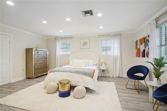 bedroom with light hardwood / wood-style floors, multiple windows, and crown molding