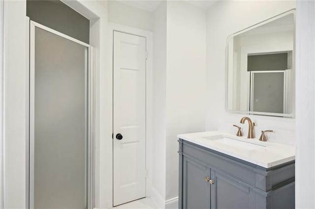 bathroom featuring a shower with shower door and vanity