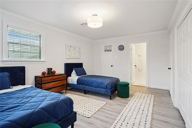 bedroom featuring a closet, ensuite bathroom, light hardwood / wood-style floors, and ornamental molding