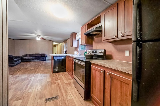 kitchen featuring under cabinet range hood, visible vents, brown cabinets, light wood finished floors, and black appliances