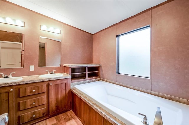bathroom featuring a bath, wood finished floors, double vanity, and a sink