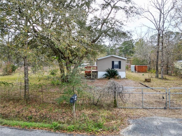 view of front of house with an outdoor structure, a gate, a storage shed, a wooden deck, and fence