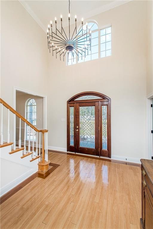 foyer featuring an inviting chandelier, crown molding, and a towering ceiling