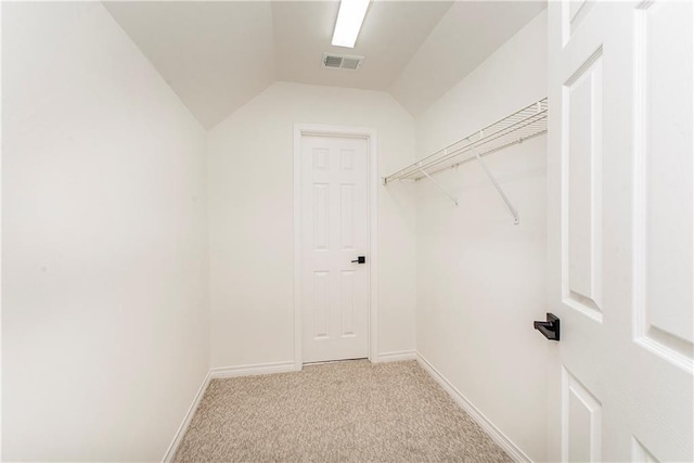 spacious closet with light colored carpet and vaulted ceiling