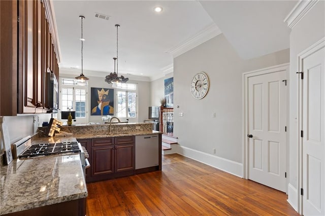 kitchen with crown molding, dark hardwood / wood-style floors, pendant lighting, stainless steel appliances, and light stone countertops