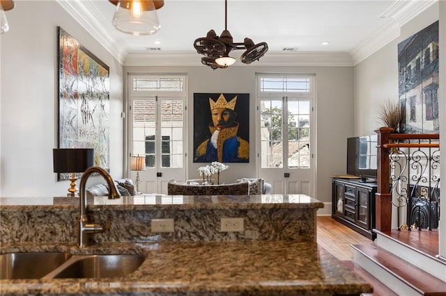 kitchen with crown molding, sink, light hardwood / wood-style flooring, and dark stone countertops