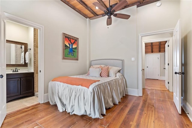 bedroom featuring sink, wood ceiling, light hardwood / wood-style flooring, beam ceiling, and ensuite bathroom