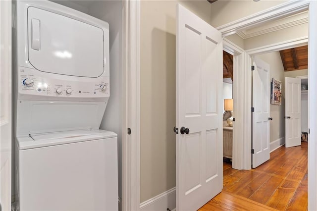 washroom featuring stacked washer / drying machine, wooden ceiling, and light wood-type flooring