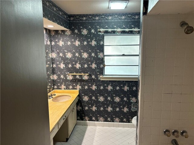 bathroom with vanity, toilet, walk in shower, wallpapered walls, and tile patterned floors