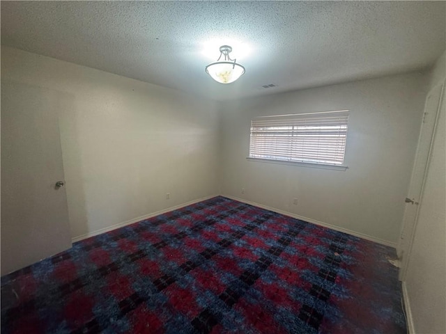 unfurnished room featuring a textured ceiling, visible vents, baseboards, and carpet