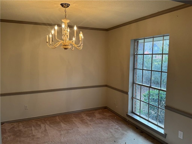 carpeted spare room with a notable chandelier, ornamental molding, and a textured ceiling