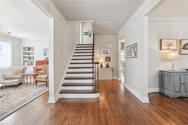 staircase with crown molding, built in features, and wood-type flooring