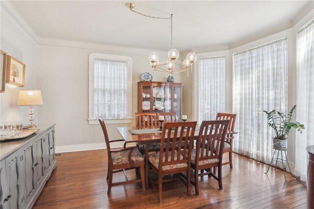 dining room featuring dark hardwood / wood-style flooring, crown molding, and a chandelier