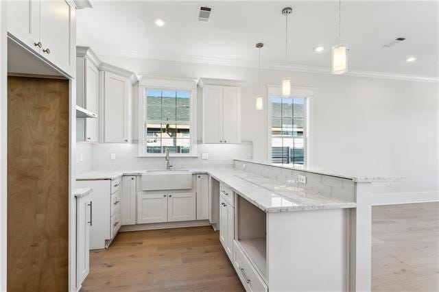 kitchen featuring pendant lighting, white cabinets, and kitchen peninsula