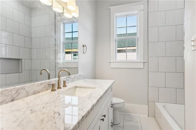 full bathroom with toilet, tile patterned flooring, tiled shower / bath, and vanity