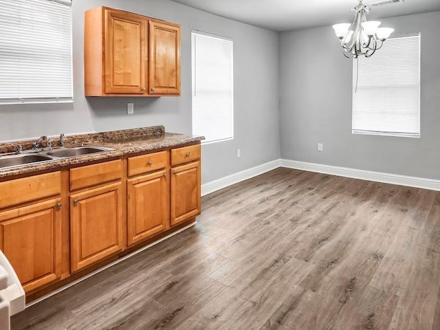 kitchen featuring a notable chandelier, dark wood-type flooring, pendant lighting, and sink