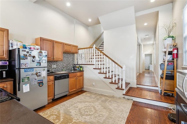 kitchen with light hardwood / wood-style floors, decorative backsplash, sink, a high ceiling, and appliances with stainless steel finishes