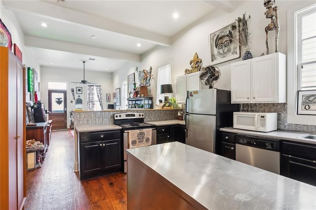 kitchen with beam ceiling, decorative backsplash, stainless steel appliances, white cabinets, and dark hardwood / wood-style flooring