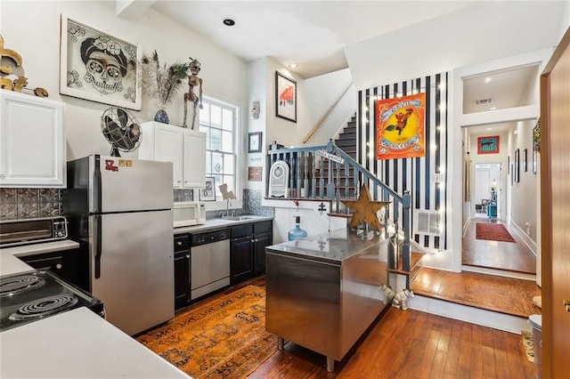 kitchen with dark wood-type flooring, white cabinetry, stainless steel appliances, decorative backsplash, and sink