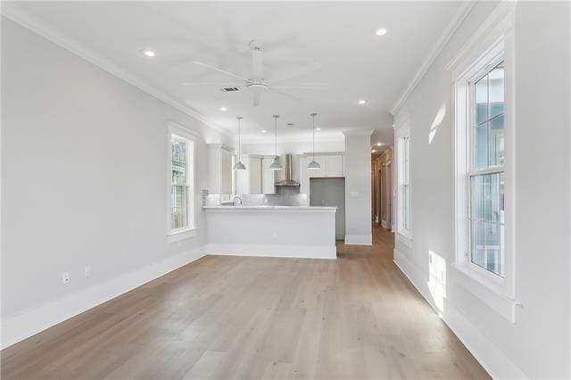 unfurnished living room featuring ceiling fan, light wood-type flooring, and ornamental molding