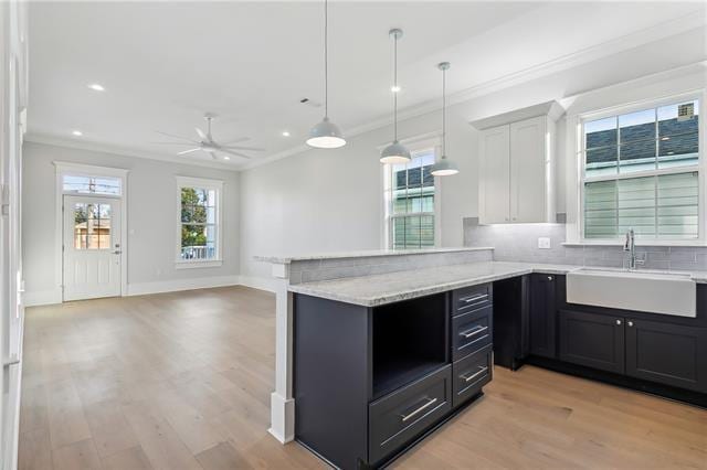 kitchen featuring decorative light fixtures, white cabinetry, sink, ornamental molding, and ceiling fan