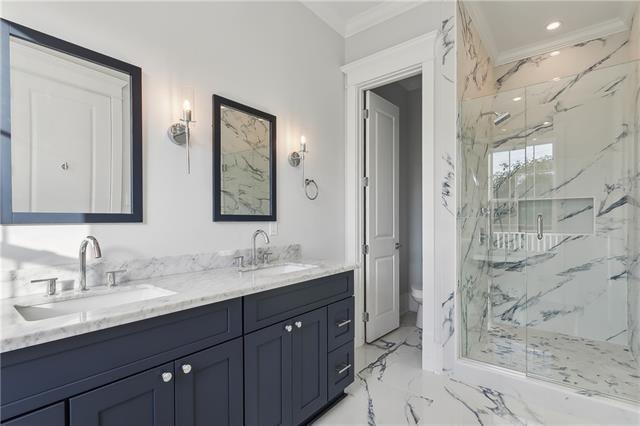 bathroom featuring toilet, vanity, crown molding, and a shower with shower door