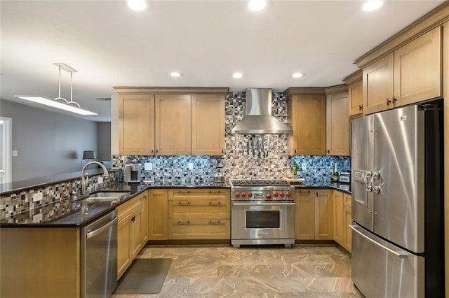 kitchen featuring wall chimney exhaust hood, sink, decorative light fixtures, dark stone countertops, and appliances with stainless steel finishes