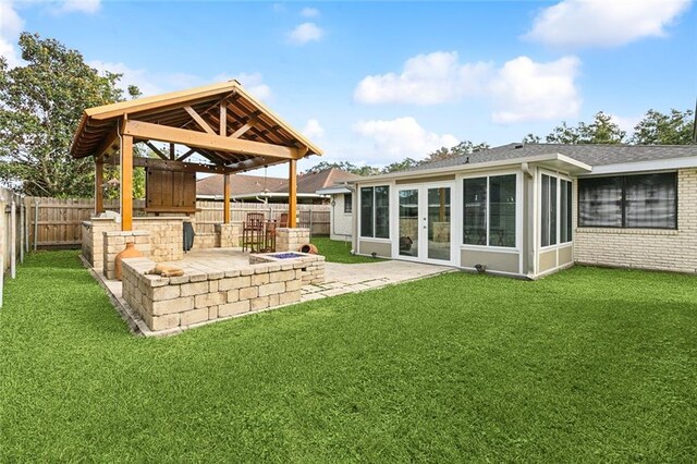 rear view of property with a gazebo, a lawn, a sunroom, and a patio