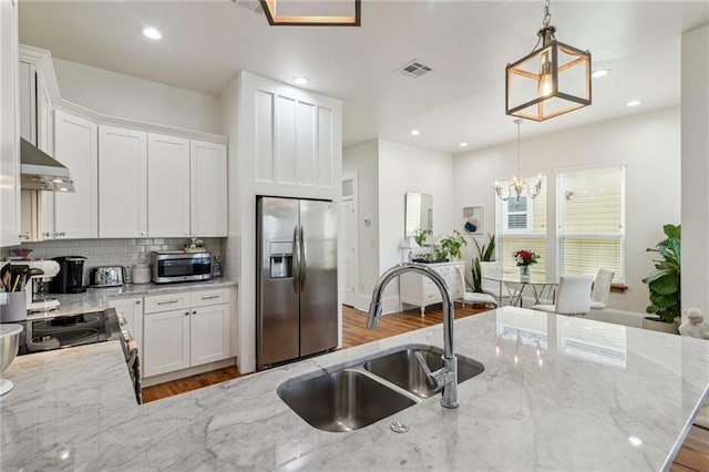 kitchen featuring appliances with stainless steel finishes, white cabinets, hanging light fixtures, and sink