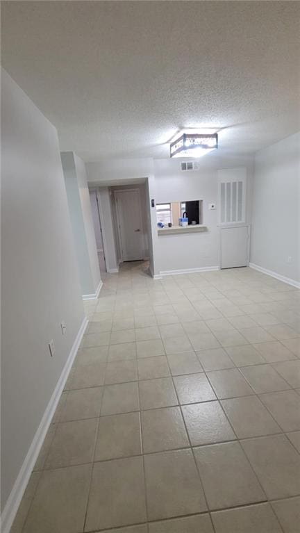 unfurnished living room with light tile patterned flooring and a textured ceiling